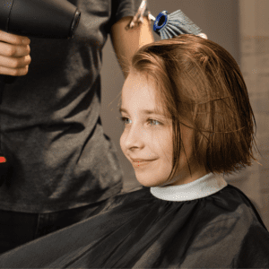 young girl getting a haircut while smiling