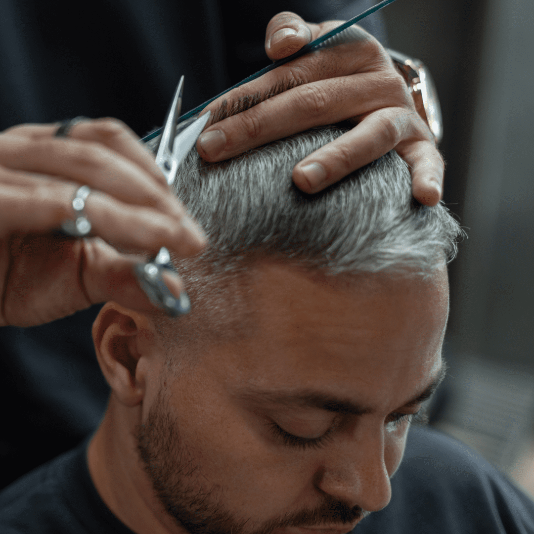 hair stylist cutting mans hair with scissors
