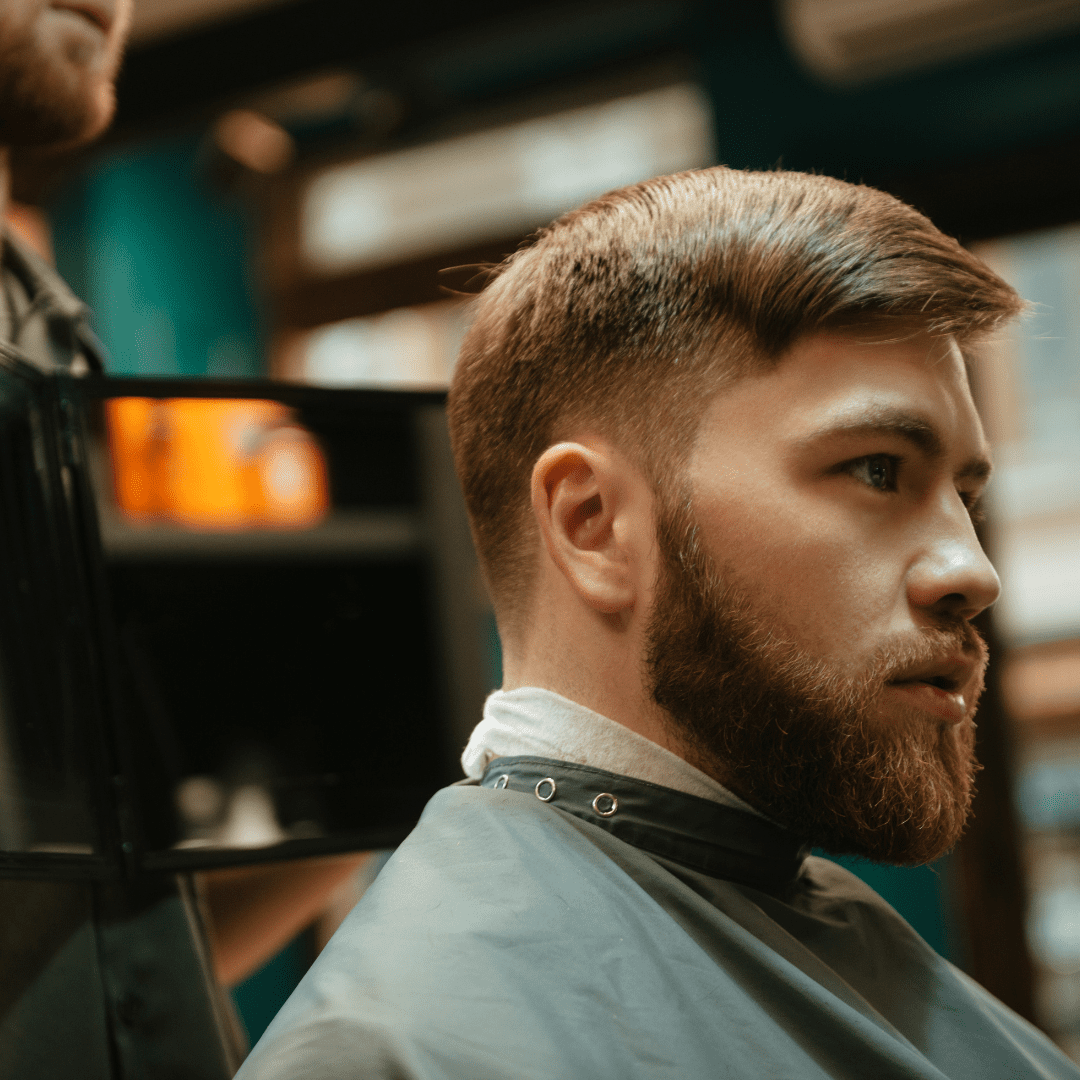 sideview of man with beard and tapered buzz cut sitting in salon chair